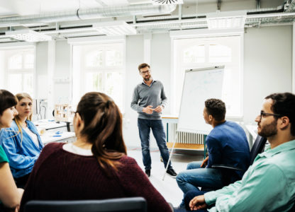 A tutor engaging and listening to his students during an engineering seminar in the lab at university.